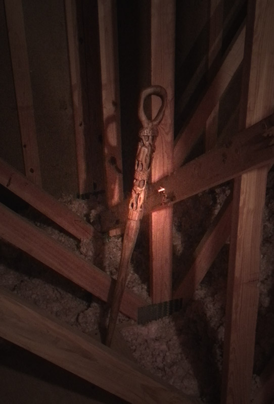 A picture of an intricately carved walking stick standing up in an attic somewhere waiting patiently for a worthy wizard to hold it once again.
